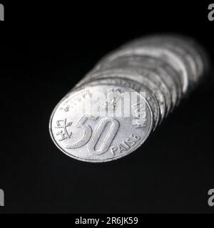 shiny vintage silver fifty or 50 paisa coins of india stacked together back to back in a row isolated in a black background in closeup Stock Photo