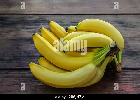 Bunches of ripe yellow bananas on wooden table Stock Photo