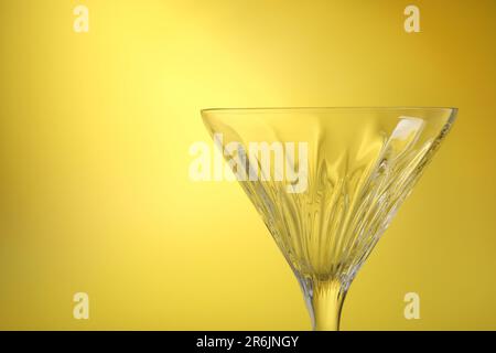 Elegant empty martini glass on yellow background, closeup. Space for text Stock Photo