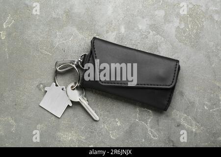 Leather case with key on grey textured table, top view. Stock Photo