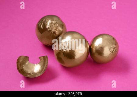 Pile of golden onions on pink background Stock Photo