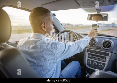 Latino man using a mobile phone inside his car. Stock Photo