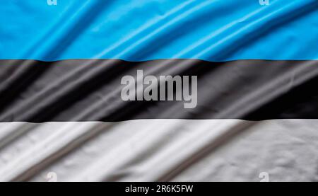 Estonia flag with big folds waving close up under the studio light indoors. The official symbols and colors in fabric banner Stock Photo