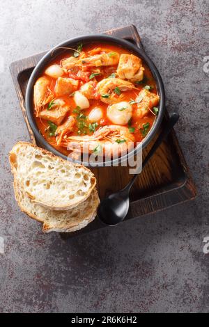 Brudet or Brodetto tasty stew of fish, seafood such as shrimps, scallops, calamari, mussels close-up in a bowl on the table. Vertical top view from ab Stock Photo