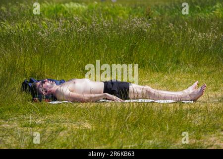 London UK. 10 June 2023 . A man sunbathes   on Wimbledon common, south west London as the hot weather continues  . The UK Health Security Agency and the Met Office have issued the first heat-health alert of the year in six regions in England, including London as temperatures are predicted to hit 30C (86F) over the weekend due to the arrival of an “Iberian plume” that will bring warm air from Spain Credit: amer ghazzal/Alamy Live News Stock Photo