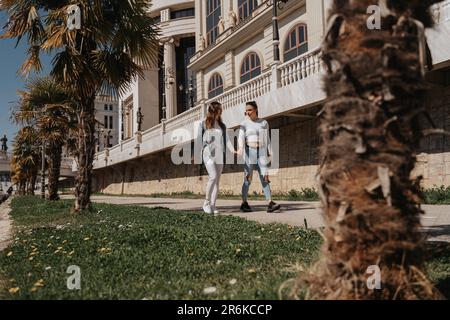 Two beautiful girls walking at the park while holding hand and having a conversation Stock Photo
