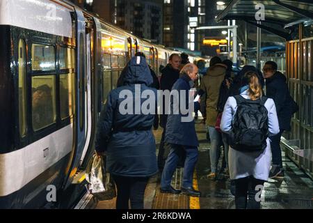 London, United Kingdom - February 01, 2019: Passengers getting on off National rail train at station platform at Lewisham during rainy cold evening Stock Photo