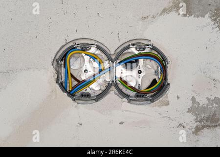 Boxes with cables for electric sockets installed in new house building empty wall, wires already covered Stock Photo