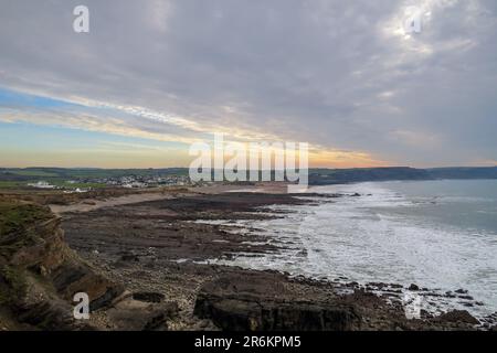 Widemouth Bay near Bude in Cornwall. The tide is out leaving a rocky  foreshore. The sandy beach can be seen in the distance... Stock Photo