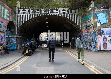 London, UK - May 17 2023:  People walk towards a graffiti covered underpass in Shoreditch, near to Shoreditch High Street Overground station Stock Photo