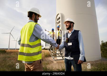 Engineers checking hands in a wind turbines farm getting into an agreement. Start new projects Stock Photo