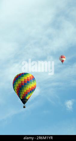 vertical photo two multi-colored balloons fly high in the sky Stock Photo