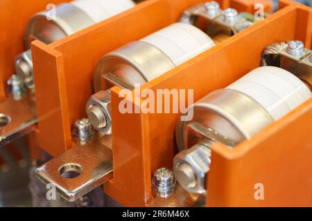 Part of high voltage electrical installation, big fuses installed inside an orange protective housing, horizontal close-up shot with selective focus, Stock Photo