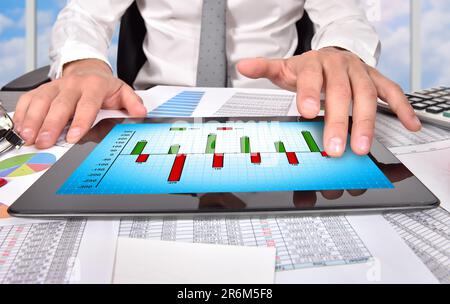 businessman hand touching digital tablet with chart of profit and cost Stock Photo