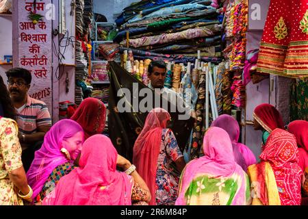 Fabric clothes vendor showing new samples to local women in Sadar Market. Jodhpur, Rajasthan, India Stock Photo
