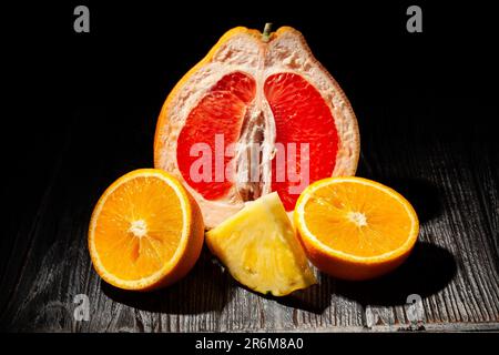 sliced tropical fruits mix on wood background Stock Photo