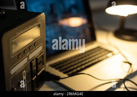 Portable power station charging gadgets on table in room. Stock Photo
