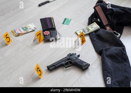 Crime scene investigation - numbering of evidences after the murdering in apartment. Brass knuckle, wallet and clothes with evidence markers Stock Photo