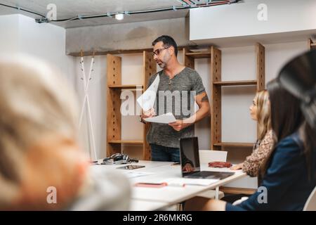 Senior man teaching and passing on his knowledge to the students at the office Stock Photo