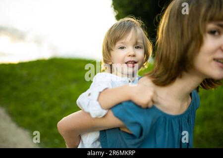 Cute big sister cuddling with her toddler brother. Adorable preteen girl piggybacking her small sibling. Children with large age gap. Siblings getting Stock Photo