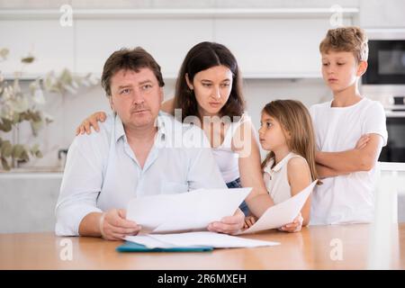 Wistful father looking through papers with family Stock Photo