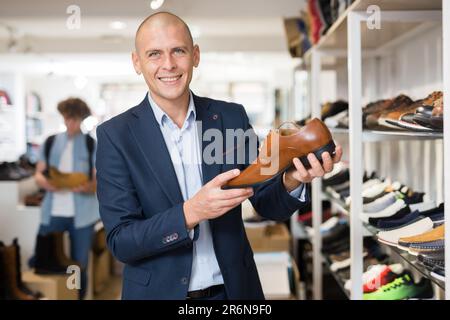 Smiling man looking for classic shoes in shoe store Stock Photo