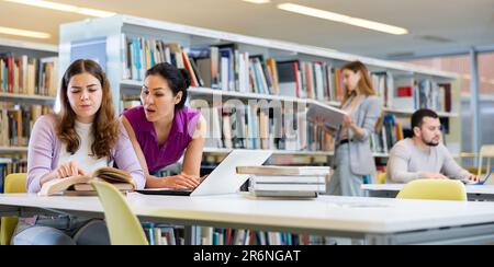 Two female colleagues working on joint project in library Stock Photo