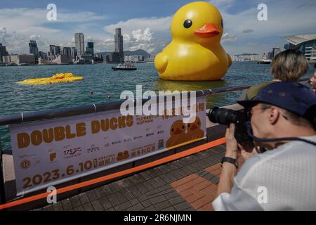 Hong Kong. 10th June 2023. A man takes photos of an enormous inflatable duck which stations at Victoria Harbour while one is deflated. Starting from June 10th, 2023, the highly anticipated art exhibition named 'Double Ducks,' created by Dutch artist Florentijn Hofman, officially opens to the public at Victoria Harbour in Hong Kong. The exhibition features two enormous inflatable ducks and marks the second visit of the giant inflatable duck to Hong Kong, with the first one having taken place a decade ago. Credit: SOPA Images Limited/Alamy Live News Stock Photo