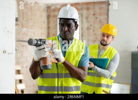 Man construction worker using demolition hammer in apartment Stock Photo