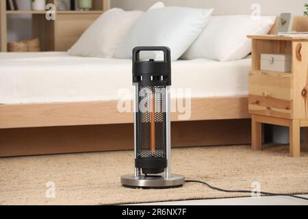 Modern infrared heater on carpet in cozy room Stock Photo
