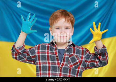 Little boy with painted hands near Ukrainian flag. Love Ukraine concept Stock Photo