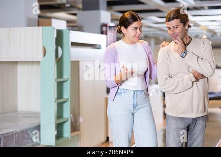 Happy man and woman choosing kids furniture in furniture showroom Stock Photo