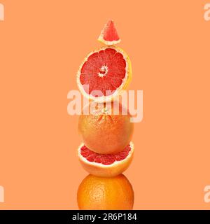 Stacked cut and whole grapefruits on orange background Stock Photo