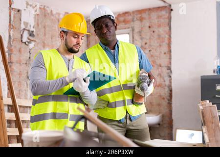 Two builders talking on indoor construction site Stock Photo