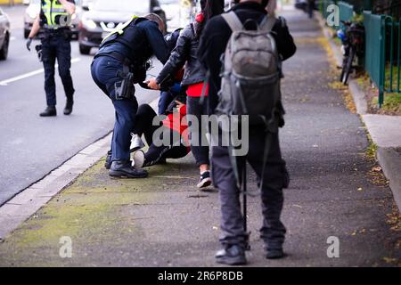 MELBOURNE, AUSTRALIA - JULY 7: A woman standing on the street in support of the residents inside of 120 Racecourse road is violently slammed to the ground and arrested as police swarm on a small number of people amid the third full day of the total lockdown of 9 housing commission high rise towers in North Melbourne and Flemington during COVID 19 on 7 July, 2020 in Melbourne, Australia. After recording a horror 191 COVID-19 cases overnight forcing Premier Daniel Andrews to announce today that all of metropolitan Melbourne along with one regional centre, Mitchell Shire will once more go back to Stock Photo