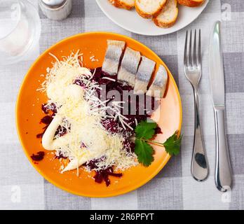 Sliced herring with grated beetroot and cheese served on table Stock Photo