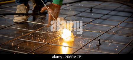 Closeup hands young worker using machine welding iron with hands working in industrial factory, welder man or labor welding joint steel while having s Stock Photo