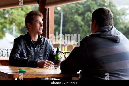 Men, friends and drinking beer at a pub and restaurant with conversation and discussion. Alcohol, guys and young people together at diner with alcohol Stock Photo