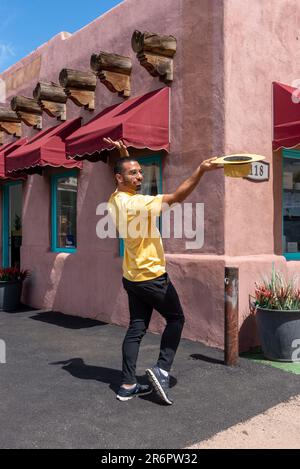 A young male poses, hat in hand, in front of a store in Santa Fe, New Mexico. Stock Photo