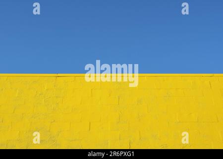 A blue sky and a strong yellow brick wall in the design of the Ukrainian flag to symbolise the strength and resilience of the Ukrainian people Stock Photo