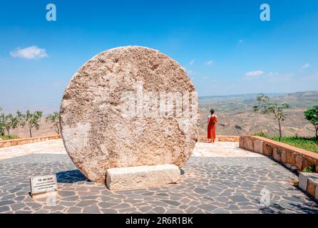 The Abu Badd, a rolling stone used as a fortified door of a Byzantine monastery in the old village of Faisaliyah. Unidentified woman enjoying the view Stock Photo