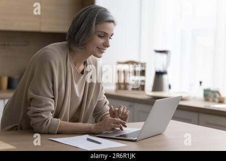 Cheerful mature freelancer woman working from home Stock Photo