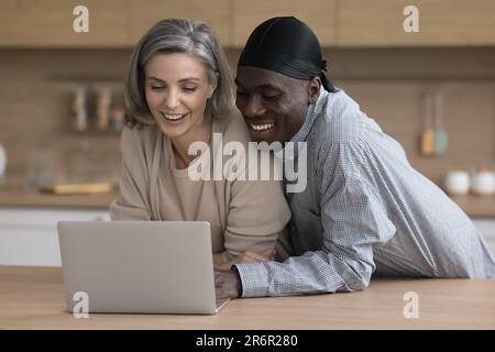 Cheerful dating couple in love using laptop at home together Stock Photo