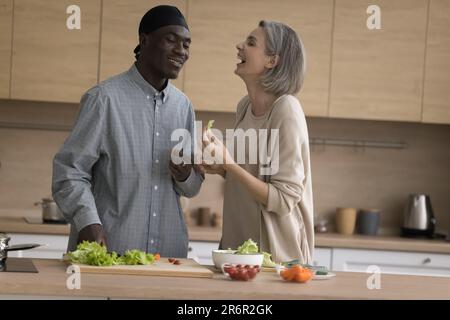 Cheerful African and Caucasian couple having fun in home kitchen Stock Photo