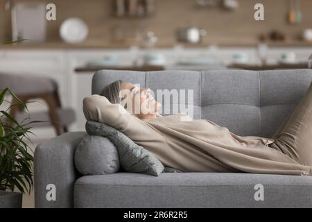 Happy relaxed mature woman resting on comfortable sofa Stock Photo