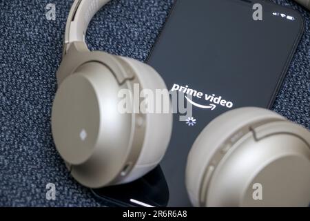 Amazon Prime Video on smartphone with logo displayed on screen, gold headphones round device, online streaming concept, Amazon Prime Video another pop Stock Photo