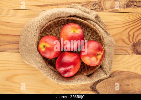 Several ripe nectarines with a jute bag on a wooden table, macro, top view. Stock Photo