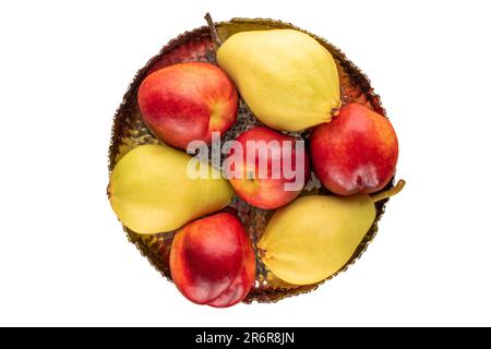 A few ripe nectarines and a pear with a metal vase on a white background, macro, top view. Stock Photo