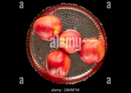 Several ripe nectarines with a metal tray on a black background, macro, top view. Stock Photo