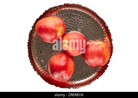 Several ripe nectarines with a metal tray on a white background, macro, top view. Stock Photo